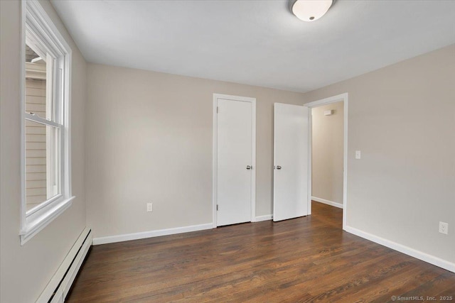 unfurnished bedroom with a baseboard heating unit and dark wood-type flooring