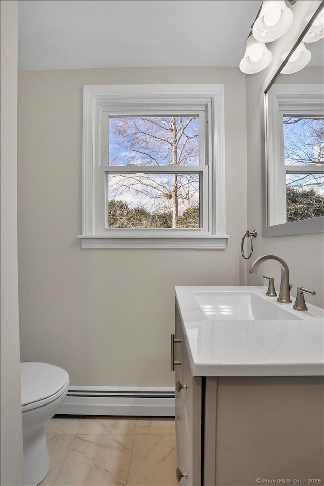 bathroom featuring a baseboard radiator, a wealth of natural light, vanity, and toilet