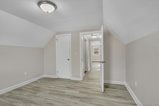 additional living space featuring vaulted ceiling, light hardwood / wood-style floors, and a baseboard radiator