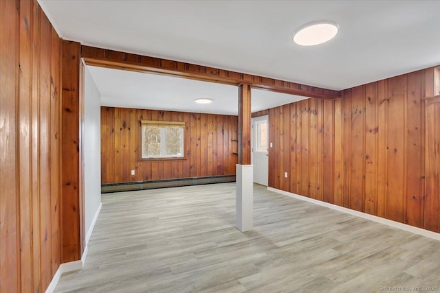 basement with baseboard heating, wooden walls, and light wood-type flooring