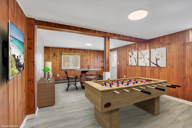 game room featuring a baseboard radiator, bar, wood walls, and light wood-type flooring