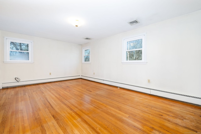 empty room featuring baseboard heating and light wood-type flooring