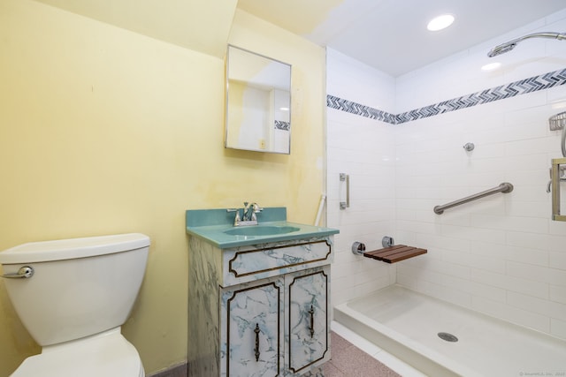 bathroom with tiled shower, vanity, and toilet