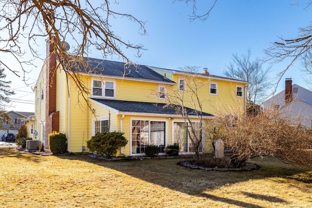 rear view of house featuring central AC unit and a yard