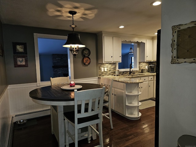 dining space with dark hardwood / wood-style floors, sink, and a baseboard heating unit