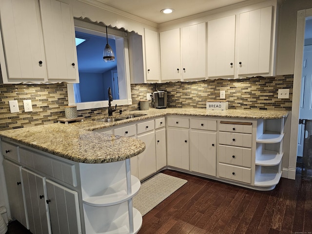 kitchen featuring pendant lighting, sink, white cabinetry, dark hardwood / wood-style flooring, and kitchen peninsula