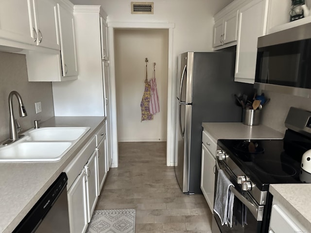 kitchen featuring appliances with stainless steel finishes, sink, light hardwood / wood-style flooring, and white cabinets