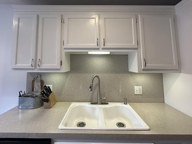 kitchen featuring light countertops, backsplash, a sink, and white cabinetry