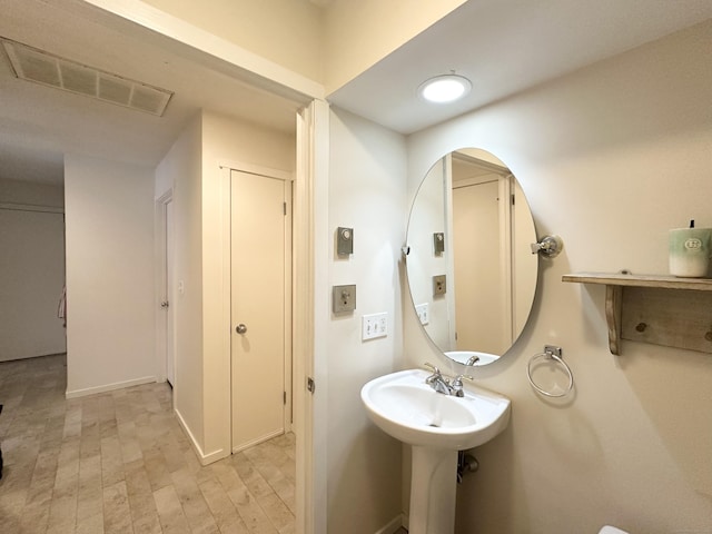 bathroom with baseboards, visible vents, and wood finished floors