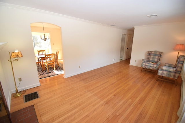 living room featuring crown molding, a notable chandelier, and light wood-type flooring