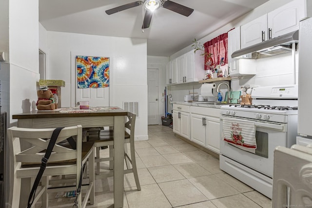 kitchen with light tile patterned floors, sink, ceiling fan, white cabinets, and white gas stove