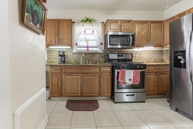 kitchen featuring dark stone countertops, sink, backsplash, and stainless steel appliances