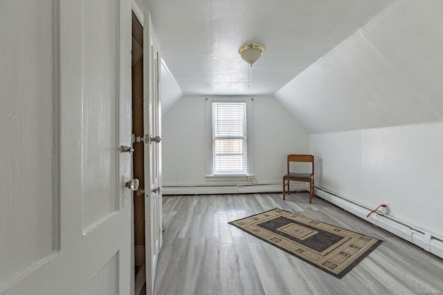 bonus room with lofted ceiling, wood-type flooring, and a textured ceiling