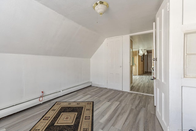 bonus room featuring lofted ceiling, a baseboard heating unit, and light hardwood / wood-style floors