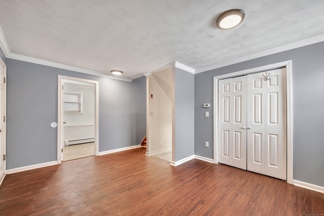 interior space with baseboard heating, ornamental molding, and hardwood / wood-style floors