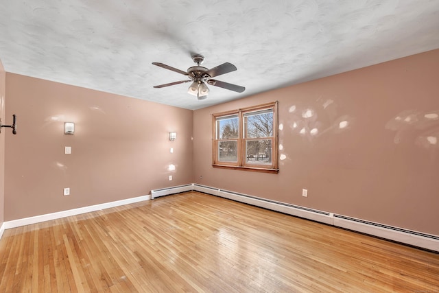 spare room with ceiling fan, a baseboard heating unit, a textured ceiling, and light hardwood / wood-style floors