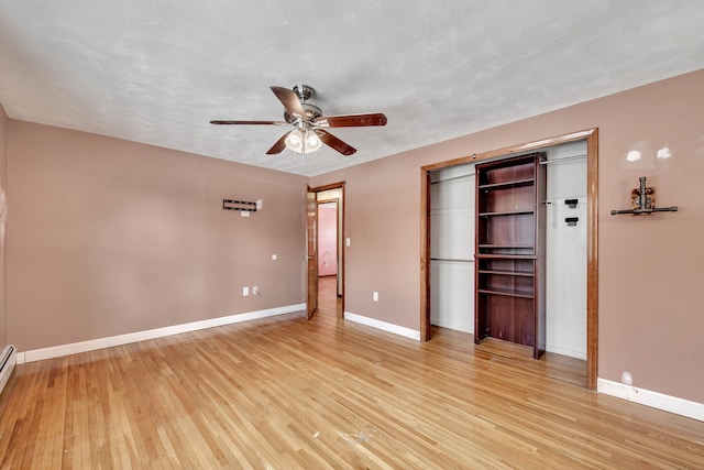 unfurnished bedroom with light hardwood / wood-style flooring, a closet, ceiling fan, and baseboard heating