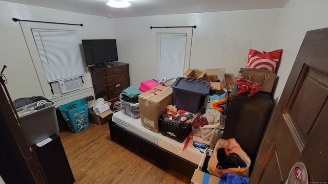 bedroom with cooling unit and light hardwood / wood-style flooring