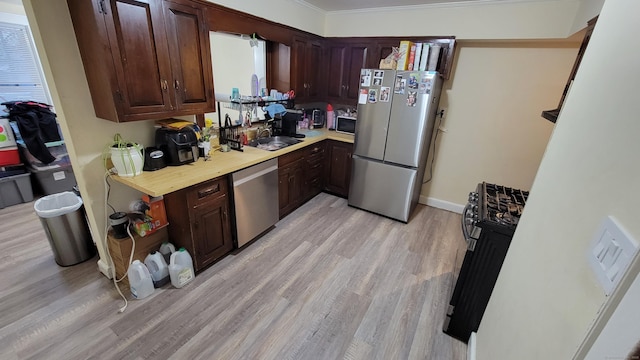 kitchen featuring dark brown cabinets, ornamental molding, light hardwood / wood-style floors, and appliances with stainless steel finishes