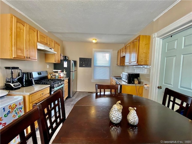 kitchen with stainless steel appliances, light brown cabinets, backsplash, and a textured ceiling