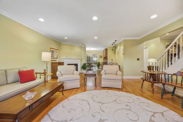 living room with ornamental molding, a notable chandelier, and light hardwood / wood-style floors