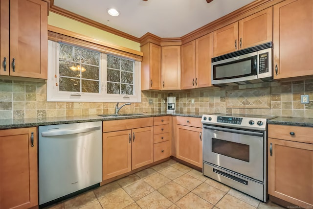 kitchen with sink, light tile patterned floors, dark stone countertops, stainless steel appliances, and decorative backsplash