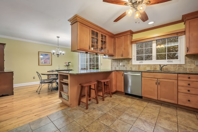 kitchen featuring a breakfast bar, sink, dark stone countertops, stainless steel dishwasher, and pendant lighting