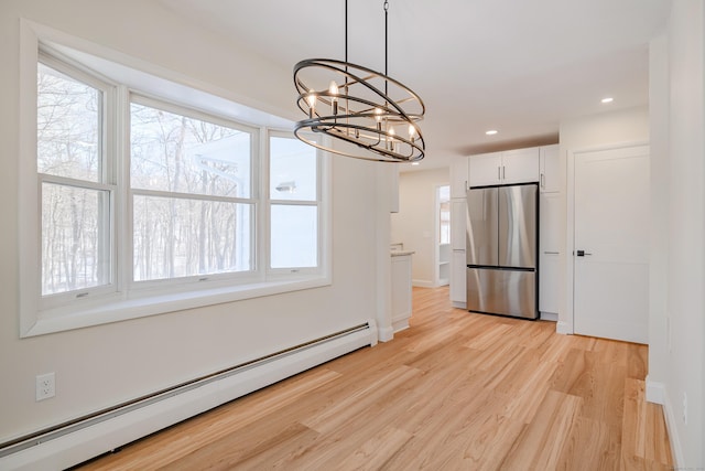 unfurnished dining area featuring a baseboard heating unit, a chandelier, and light wood-type flooring