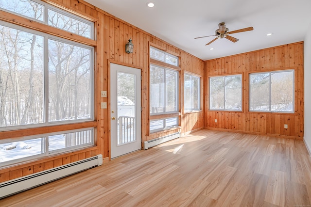 unfurnished sunroom featuring a wealth of natural light, a baseboard radiator, and ceiling fan