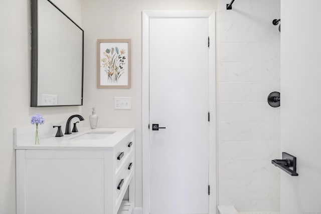 bathroom featuring tiled shower and vanity