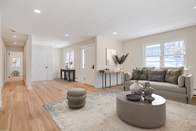 living room featuring a baseboard heating unit, light hardwood / wood-style floors, and a healthy amount of sunlight