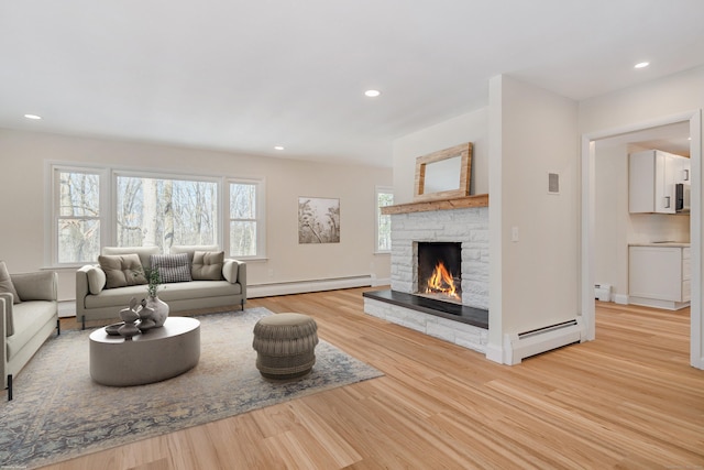 living room featuring a baseboard radiator, a fireplace, and light hardwood / wood-style flooring