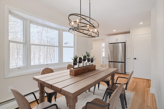 dining space featuring an inviting chandelier, baseboard heating, and light wood-type flooring