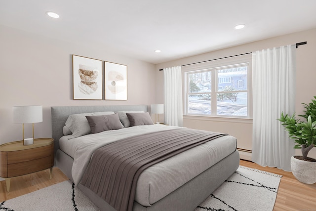 bedroom featuring a baseboard heating unit and light wood-type flooring