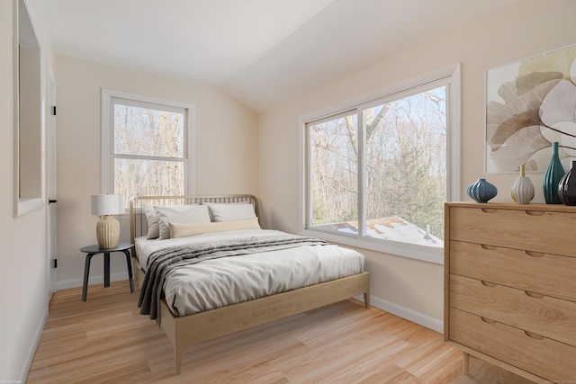 bedroom with multiple windows, vaulted ceiling, and light hardwood / wood-style floors