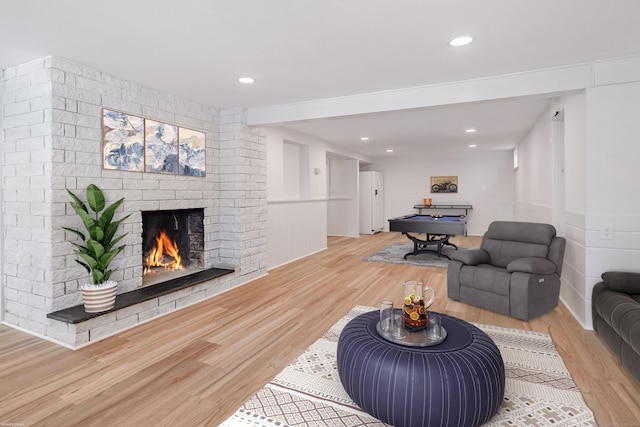 living room with hardwood / wood-style flooring, billiards, and a brick fireplace