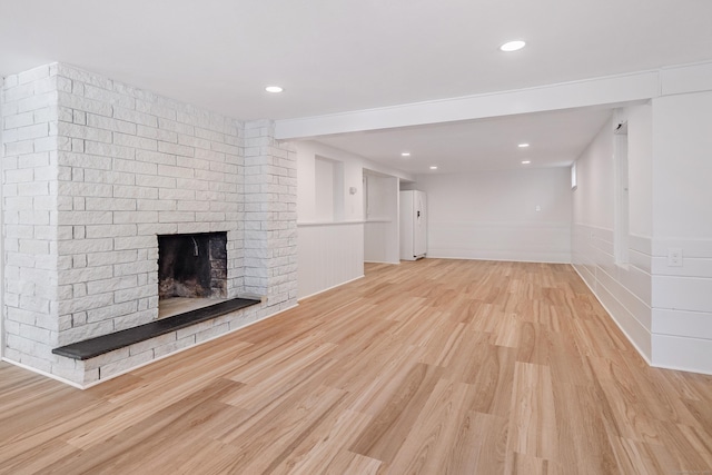 unfurnished living room with a brick fireplace and light hardwood / wood-style flooring