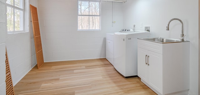 clothes washing area featuring washing machine and dryer, sink, and light wood-type flooring