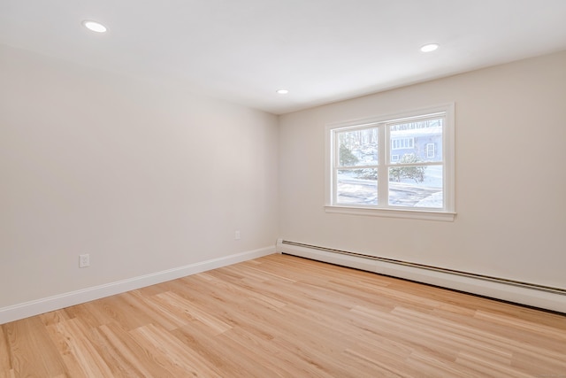 unfurnished room featuring a baseboard radiator and light wood-type flooring