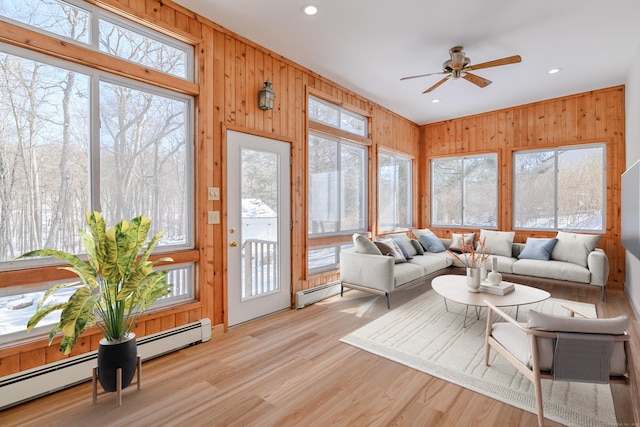 sunroom / solarium with a baseboard heating unit, a healthy amount of sunlight, and ceiling fan