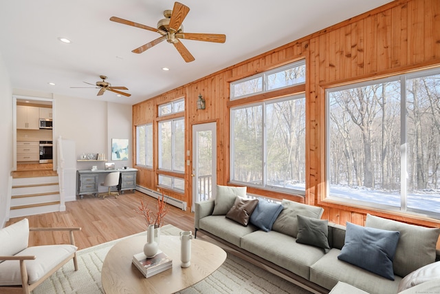 living room with wooden walls, light hardwood / wood-style flooring, and a baseboard heating unit