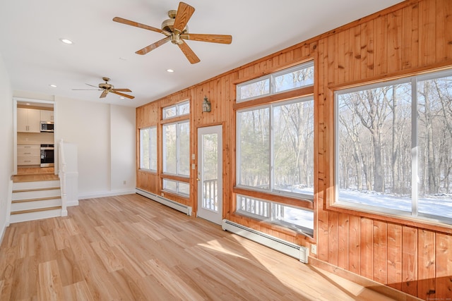 unfurnished sunroom featuring ceiling fan and baseboard heating