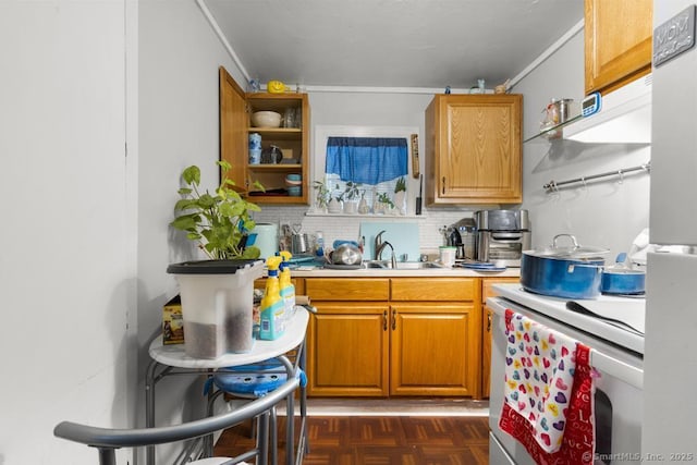 kitchen with dark parquet flooring, sink, tasteful backsplash, range, and stainless steel fridge