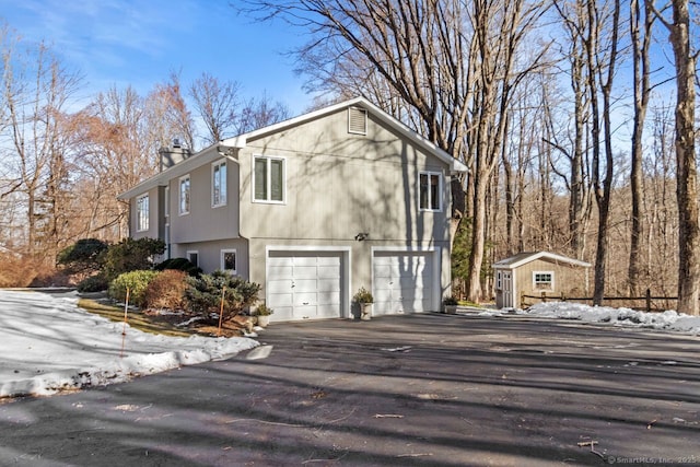 snow covered property featuring a garage and a storage unit