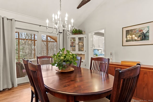 dining room featuring an inviting chandelier, lofted ceiling, and light wood-type flooring