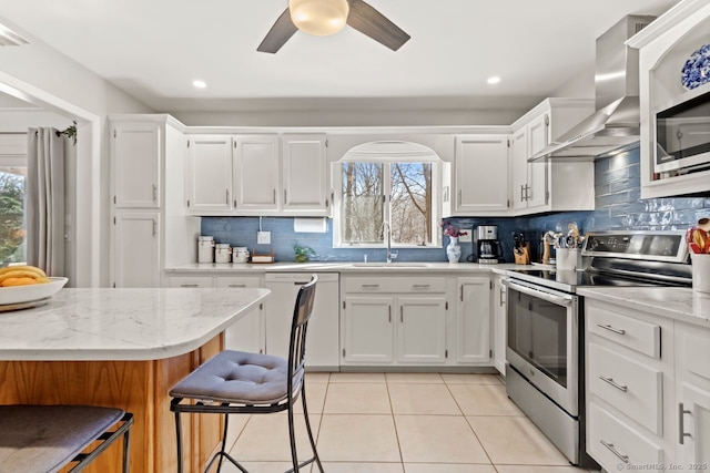 kitchen with sink, stainless steel appliances, light stone countertops, white cabinets, and wall chimney exhaust hood