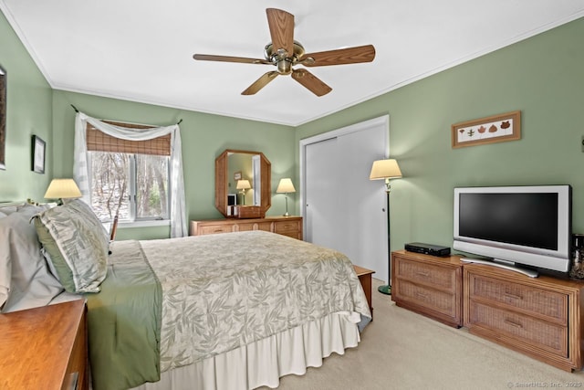 bedroom with ceiling fan, a closet, ornamental molding, and light carpet