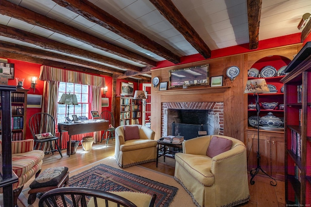 living area with hardwood / wood-style flooring, a fireplace, and beam ceiling