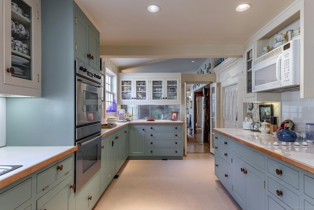 kitchen with backsplash, white appliances, light countertops, and vaulted ceiling