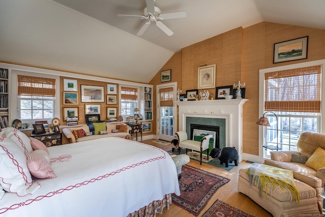 bedroom with multiple windows, hardwood / wood-style flooring, a fireplace, and vaulted ceiling